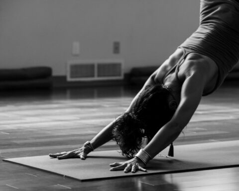 woman in black tank top and black pants bending her body on floor